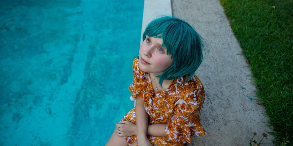 Eliza Scanlen sits by the swimming pool in the film Babyteeth