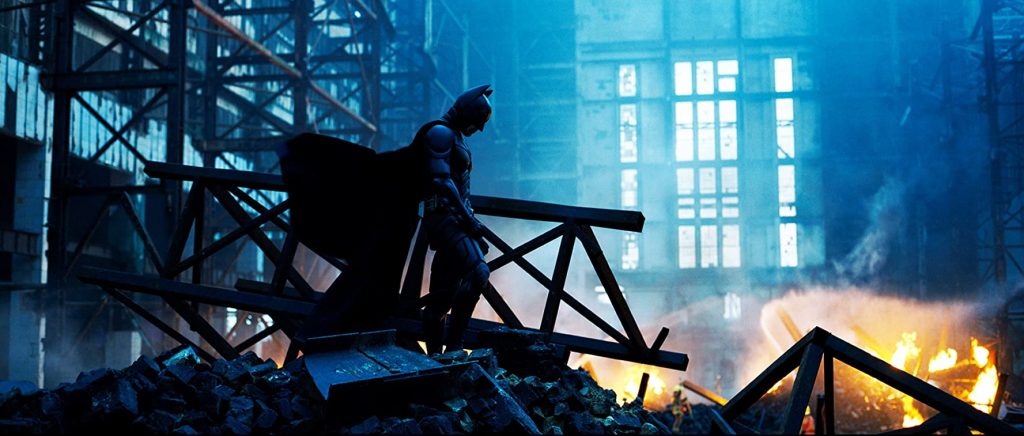 Christian Bale in The Dark Knight surrounded by fire and wreckage