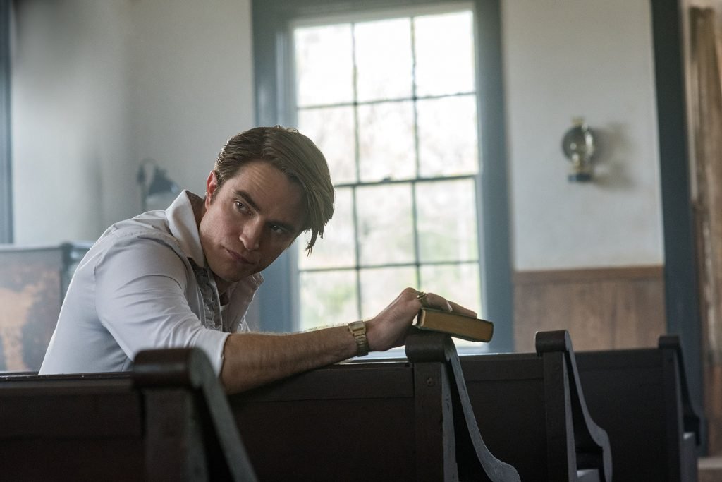 Robert Pattinson holds a bible in a church as Preston Teagardin in The Devil All The Time