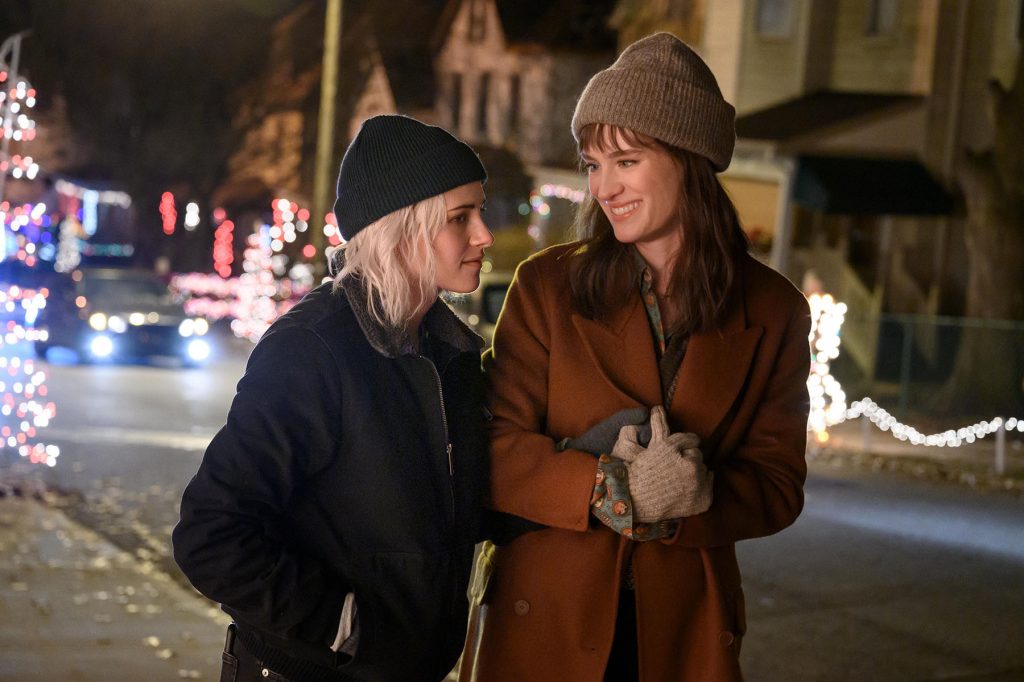 Abby (Kristen Stewart) and Harper (Mackenzie Davis) hold hands in Happiest Season