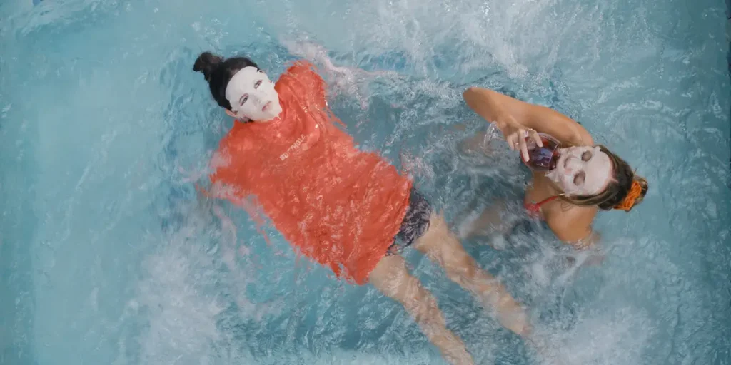 Two girls wear a face mask in the swimming pool in a still from the movie The Fallout