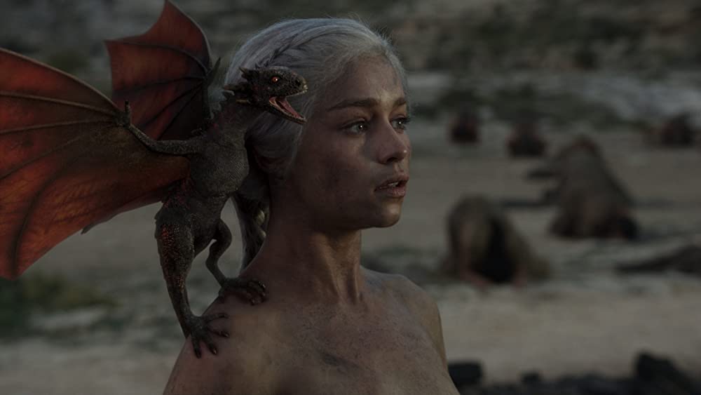 Emilia Clarke with a dragon on her shoulder in Game of Thrones