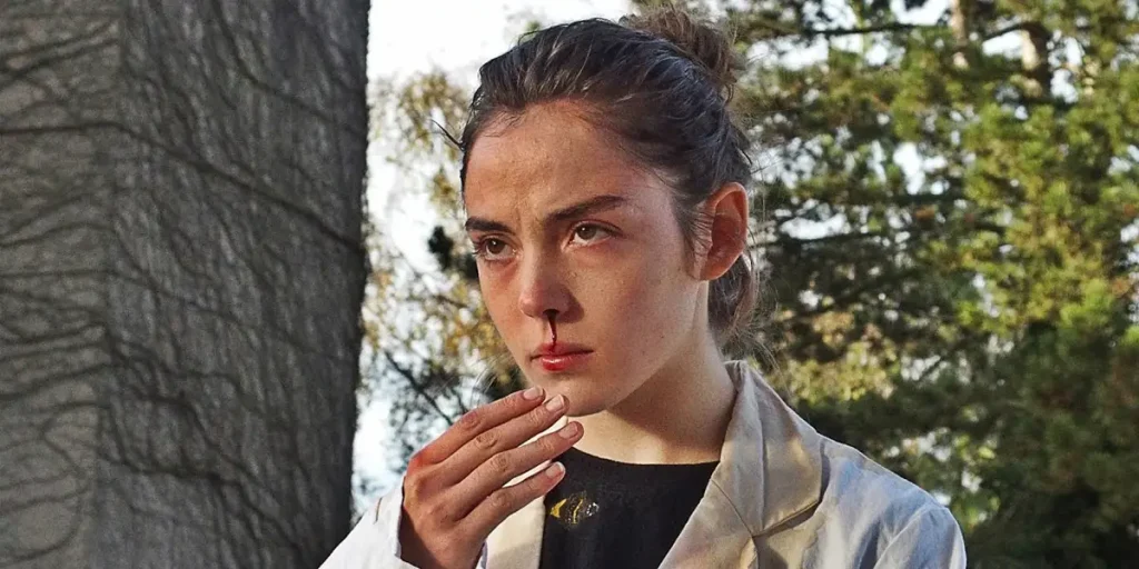 Justine (Garance Marillier) holds out a hand and bleeds from her nose in a still from the movie "Raw"