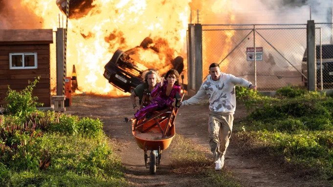 Brad Pitt, Channing Tatum and Sandra Bullock running away from fire in The Lost City