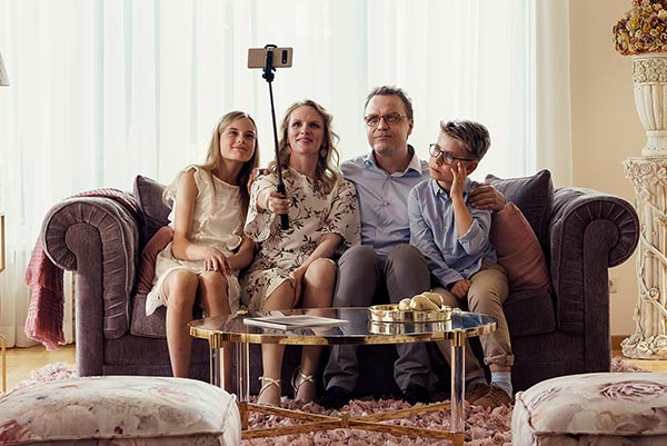 A family sits on a sofa taking a picture together in a still from Hanna Bergholm’s Hatching