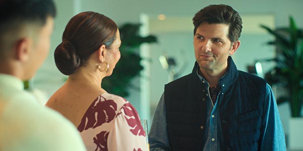 Joel Kim Booster, Maya Rudolph and Adam Scott look at each other in the film “Loot”