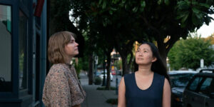 Two girls stand outdoors looking up in a still from Showing Up