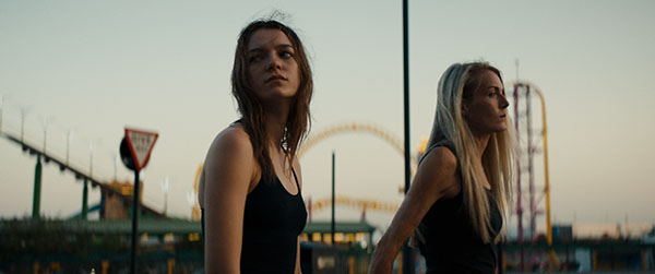 Two girls stand outside with some constructions behind them in a still from the film Silver Haze