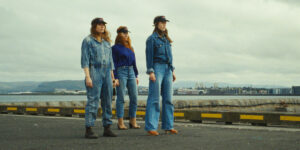 Three girls stand at an airport in a still from Álfrún Örnólfsdóttir’s film Band