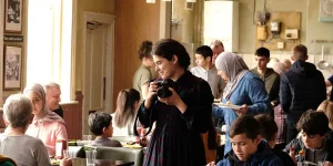 A woman holds a camera in a still from the film The Old Oak