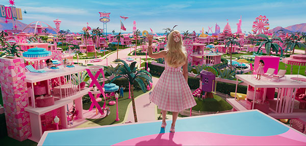 Margot Robbie waves dressed in pink and looking over Barbietown in the film Barbie, one of the films that will, could or should win the Oscars 2024 according to Loud and Clear Reviews' predictions