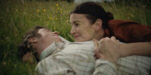 A man and a woman lay on the grass in a still from the film That They May Face The Rising Sun, whose protagonists, Barry Ward and Anna Bederke, we interview