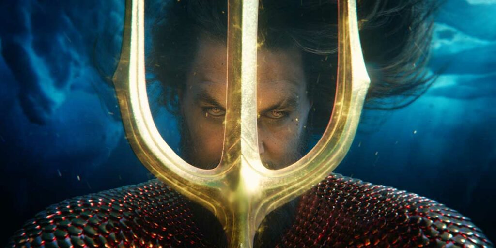 Joason Momoa holds a trident in front of his face in the film Aquaman 2
