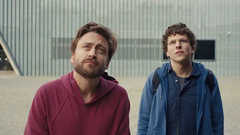 Kieran Culkin and Jesse Eisenberg look up in the film A Real Pain