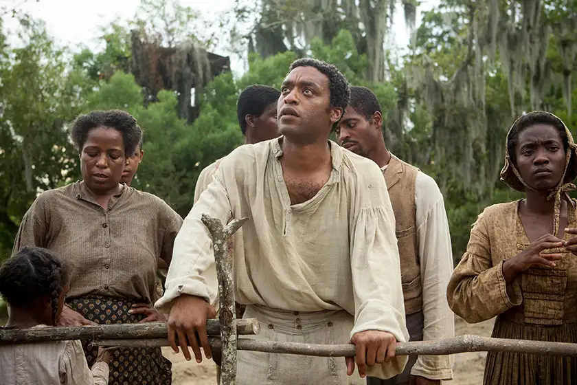 Chiwetel Ejiofor leans on a fence and looks up in 2014 Best Picture nominee 12 Years a Slave
