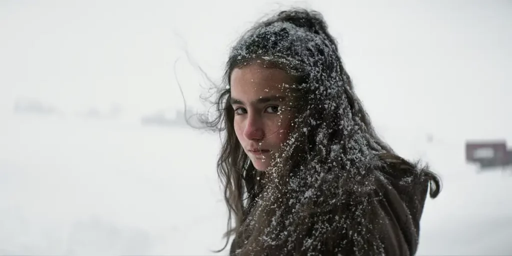 A character looks at the camera covered in snow in the film About Dry Grasses