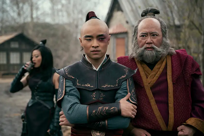 Dallas Liu as Prince Zuko stands with his arms crossed, with Arden Cho as June and Paul Sun-Hyung Lee as Iroh at his sides, in season 1 of Avatar: The Last Airbender