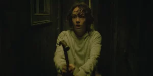 Brigette Lundy-Payne holds a hammer in the darkness in the film Amelia's Children