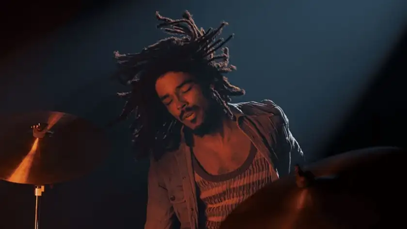 Kingsley Ben Adir plays the drum in a scene from the movie Bob Marley: One Love