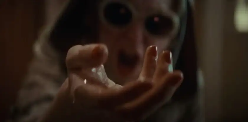 A scary figure holds out a hand with slimy liquid on it in the horror film Cuckoo