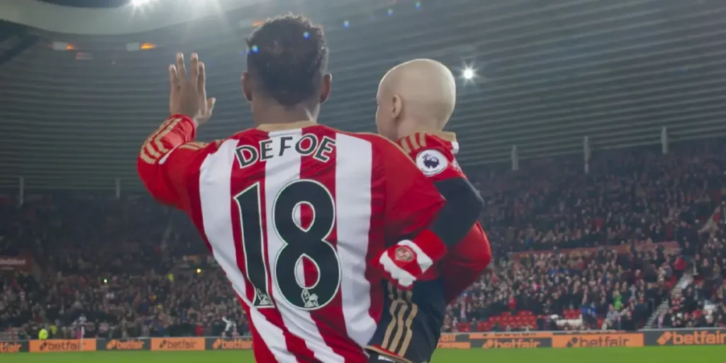 Jermain Defoe waves to the stadium holding his child in the documentary Defoe