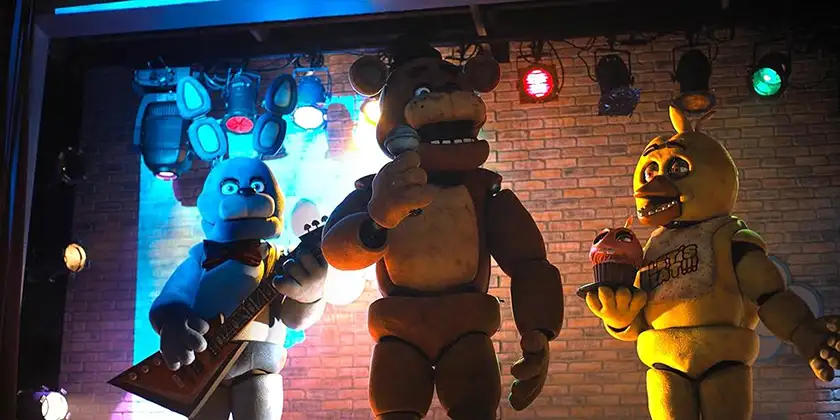 Three main characters of the film Five Nights at Freddy's, standing under the lights