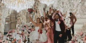 Jennifer Lopez is dressed as a bride and holding a bouquet, running with many people in The Greatest Love Story Never Told