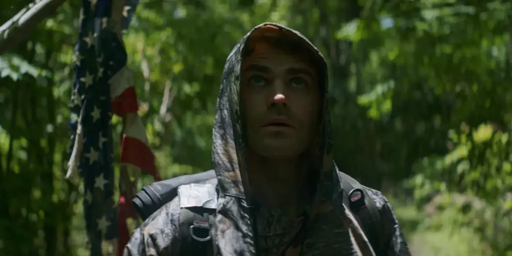 Paul shudder wears a hooded jacket in a forest in the Shudder film History of Evil