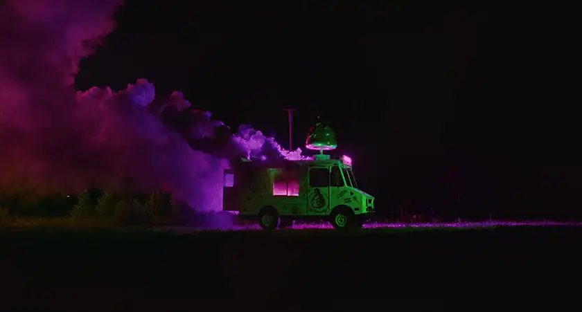 A green truck has pink smoke coming out of it at night in the film I Saw The TV Glow