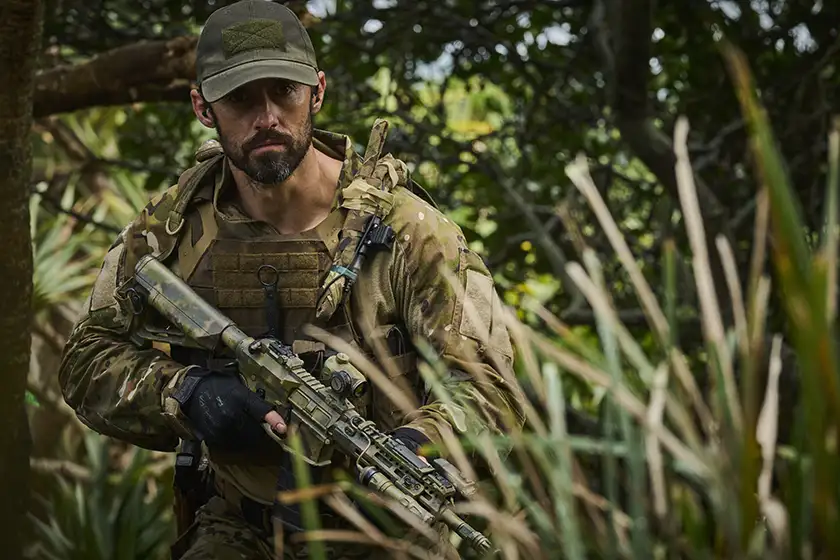 Milo Ventimiglia holds a rifle as Sugar in the action film Land of Bad