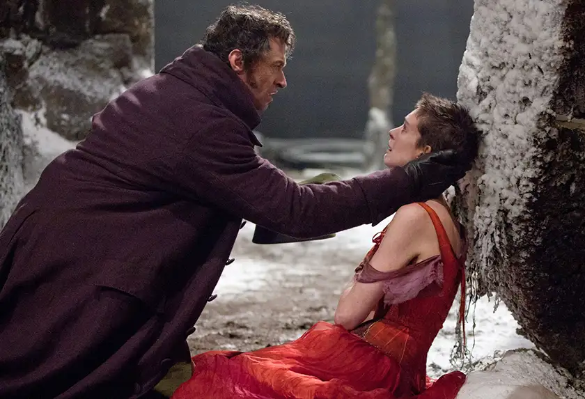 Hugh Jackman puts a hand on Anne Hathaway's face in the film Les Misérables