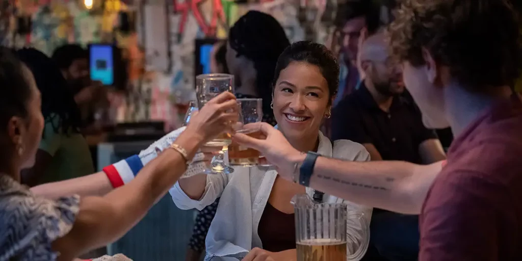 Gina Rodriguez clinks glasses with her friends in the Netflix film Players