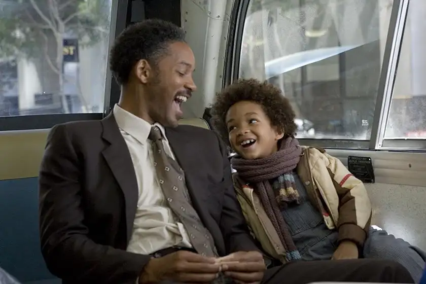 Will Smith and his son laugh sitting on a train in The Pursuit of Happyness
