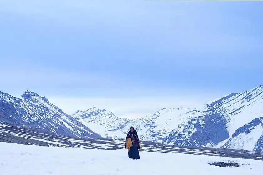 Thinley Lhamo walks alone in the snow surrounded by mountains in the film Shambhala