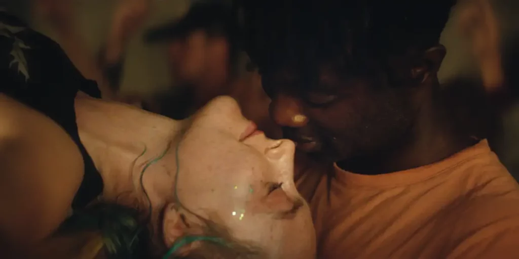 A white girl and a black boy have their heads close together while dancing in the film The Outrun