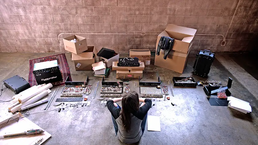 Alison Tavel sits on the floor with synthesizers in front of her in the film Resynator