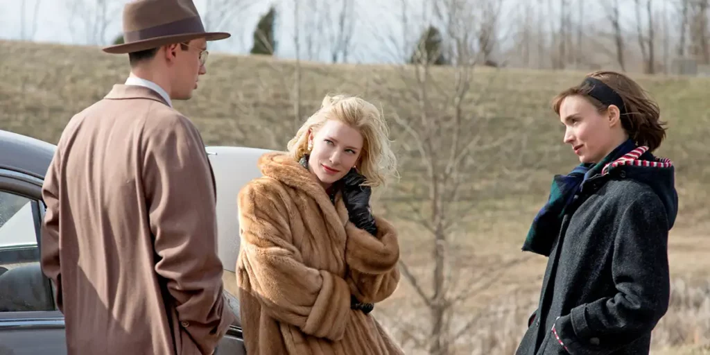 Cate Blanchett and Rooney Mara look at a man in front of a car in Carol