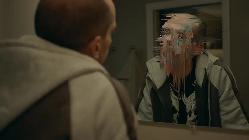 A man looks in the mirror and sees a distorted image of himself in the Paramount+ series CTRL+ALT+DESIRE, one of the 10 Best New Shows to Watch in April 2024 according to Loud and Clear Reviews