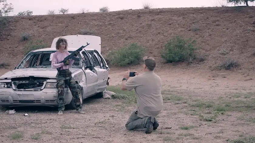 A man photographs a woman holding a rifle in the documentary film Danger Zone