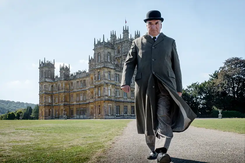 Jim Carter as Mr. Carson in front of the Downton Abbey castle
