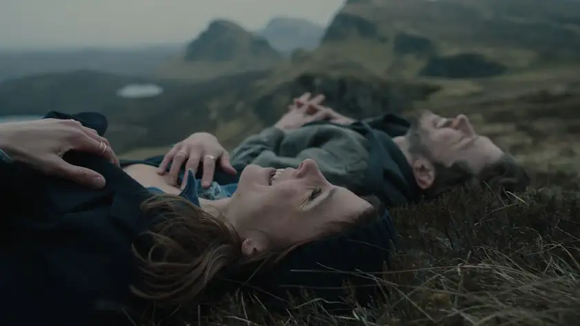 two characters laugh lying in the grass in the film Falling Into Place