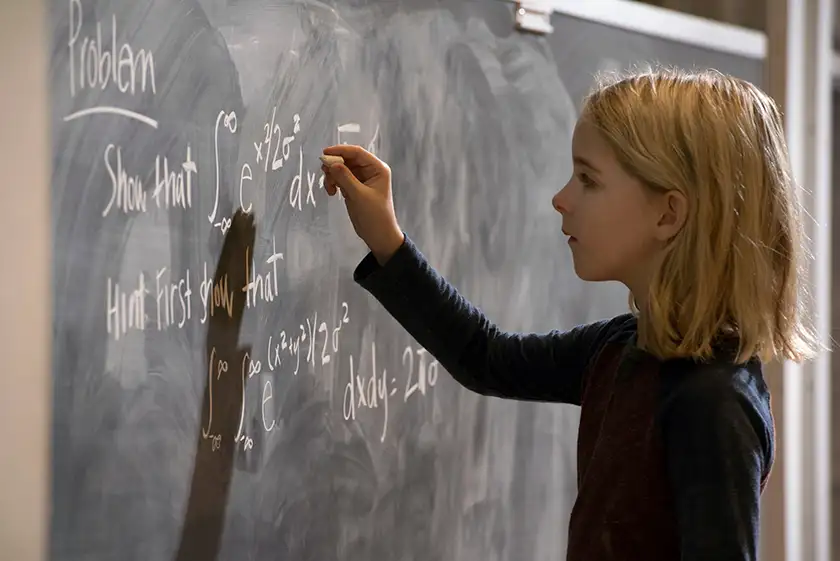A young child writes on a blackboard in the film Gifted