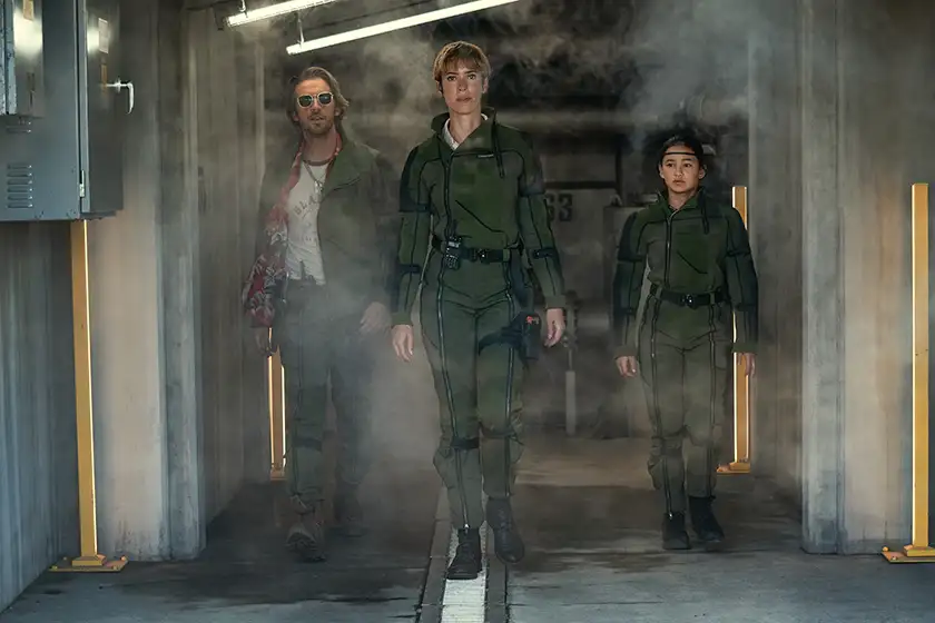DAN STEVENS as Trapper, REBECCA HALL as Dr. Ilene Andrews and KAYLEE HOTTLE as Jia walk in a corridor in “GODZILLA x KONG: THE NEW EMPIRE”