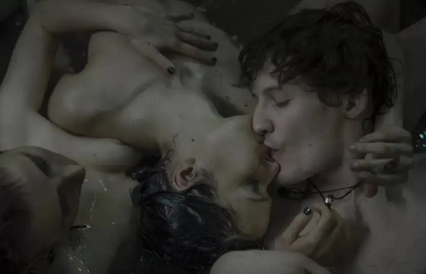 Two naked people kiss, leaning on a third, in the film Imago