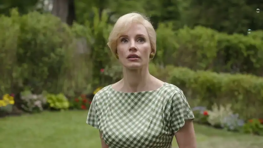 Jessica Chastain wears a green dress in the garden and looks up in the film Mothers' Instinct
