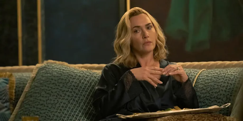 Kate Winslet sits on a sofa holding her hands togerher in season 1 episode 2 of The Regime