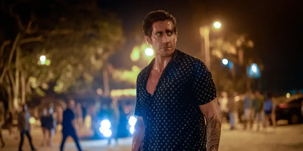 Jake Gyllenhaal looks to his left outdoors in the night in the film Road House (2024)
