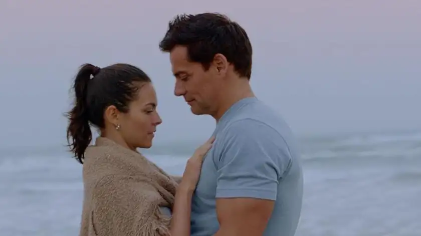A woman has her hands on a man's chest in a loving way, by the beach, in the film Switch Up