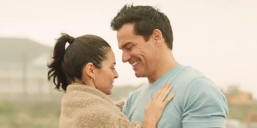 A woman has her hands on a smiling man's chest in a loving way, by the beach, in the film Switch Up