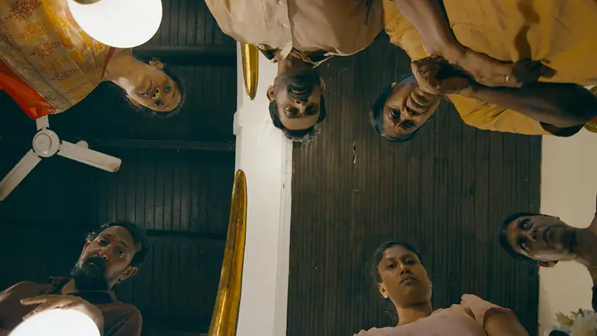 six people look down at the camera from above in a shot from the film Tentigo